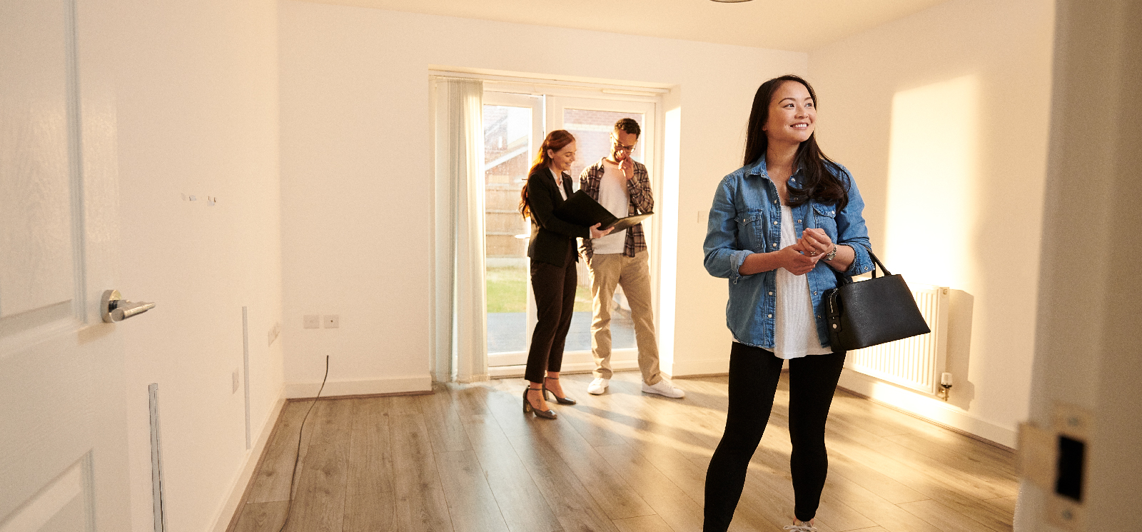 IMAGE: Couple walking into new home with realtor showing them around